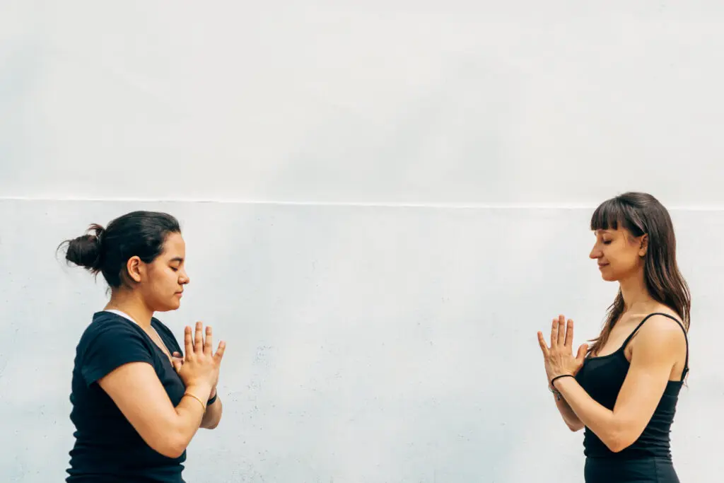 Two women practicing yoga facing each other.