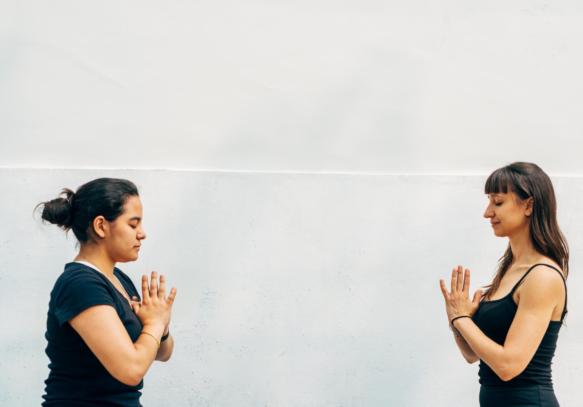 Two women practicing yoga facing each other.